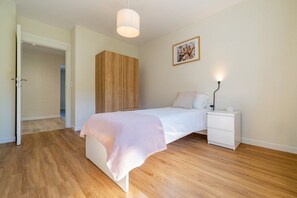 Ein Schlafzimmer mit Bett, Nachttisch, Kleiderschrank und einer Pendelleuchte.