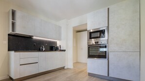 A modern kitchen with built-in appliances, a black countertop, and light wood flooring. - Leaf Apartment in Zurich Oerlikon (Zürich)