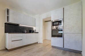 A modern kitchen with built-in appliances, a black countertop, and light wood flooring. - Leaf Apartment in Zurich Oerlikon (Zürich)