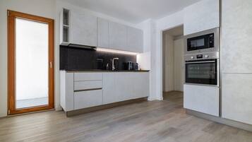 Eine moderne Küche mit weißen Schränken, einer schwarzen Arbeitsplatte und Edelstahlgeräten, darunter eine Mikrowelle und ein Backofen.