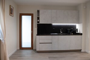 A modern kitchen with grey cabinets, a black countertop, and a built-in coffee maker. - Pure living Apartment in Zürich Oerlikon (Zürich)