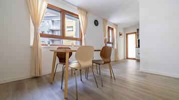 Ein Essbereich mit Tisch und Stühlen, Holzboden und Blick durch das Fenster.