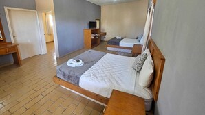 Una camera d'albergo con due letti, una televisione, una scrivania e un armadio.