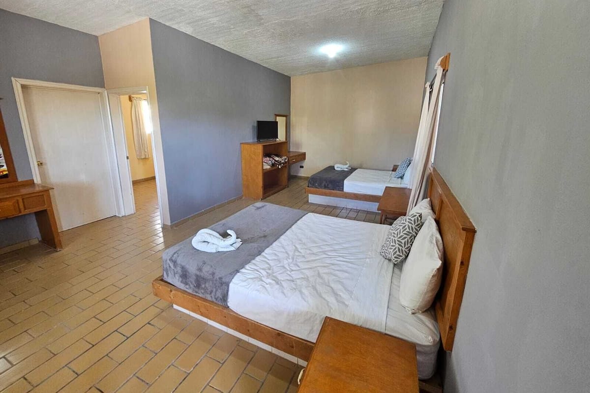 A hotel room with two beds, a TV, a desk, and a wardrobe.