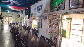Un restaurante con una larga mesa de comedor y sillas, carteles en las paredes y una barra con varios artículos.