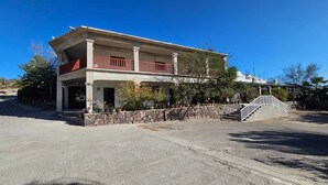 Un edificio a due piani con un balcone, un muro in pietra e una scala che conduce a un livello superiore.
