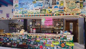 Un bar con un neon che recita 'Mamacita Margarita' e un muro decorato con diversi adesivi e poster.