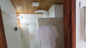 Un baño con cabina de ducha de vidrio, inodoro y techo de madera.
