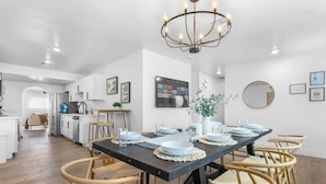 Een eetruimte met een donker houten tafel, gedekt voor zes personen, omringd door rieten stoelen.