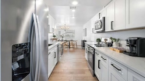 Een moderne keuken met witte kasten, roestvrijstalen apparatuur en een houten vloer.