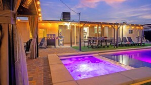 Un espace piscine doté d’un jacuzzi, de coins salon extérieurs et d’une terrasse couverte.
