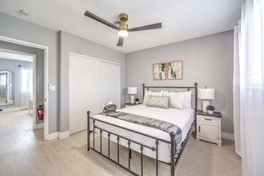 Ein Schlafzimmer mit einem Bett, Nachttischen, einem Deckenventilator und einem Feuerlöscher.