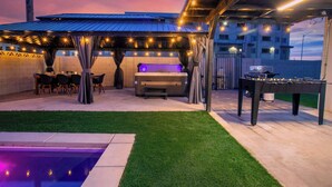 An outdoor patio with a barbecue, seating area, and a pool. - Grand 8BR Oasis – Pool, Spa, Arcade Games (North Las Vegas)