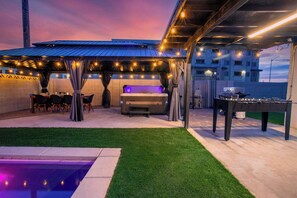 Eine Terrasse im Freien mit Grill, Sitzgelegenheit und Pool.