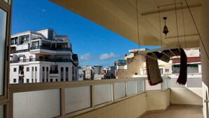 Ein Balkon mit Blick auf moderne Gebäude, einer hängenden Leuchte und einem Balkongeländer.