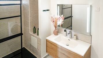 A bathroom with a shower, a sink with a mirror, and toiletries.