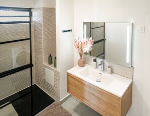 Un bagno con doccia, lavandino con specchio e articoli da toilette.