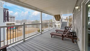 Varanda coberta com grades de madeira, um deck de madeira e vista para uma área residencial.