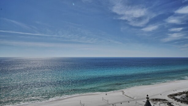 Une plage avec un ciel dégagé et une mer calme.