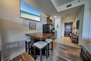 A kitchen with a wooden island, bar stools, and a view of the beach through a large window. - Rooftop Pool Hot Tub Arcade Coffee Shop and Great Location! (Panama City Beach)