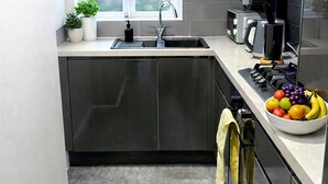 Una cucina moderna con lavello integrato, una finestra con persiana scura e un piano di lavoro con una ciotola di frutta.
