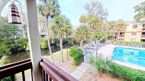 A poolside view with a river, palm trees, and a building with balconies. - FANTASTIC FIND! Great deals and in the heart of everything! Beaches, golf, shops (Hilton Head Island)