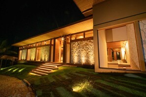 A modern building with a stone facade, large windows, and a well-lit entrance. - Alto do Mucugê, an exclusive residence perched on the cliffs of Arraial d'Ajuda. (Arraial d'Ajuda)