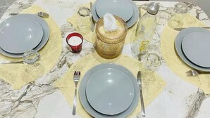Une table dressée avec des assiettes, des couverts et une bougie.