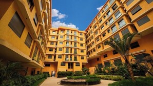 Un immeuble à plusieurs étages doté de balcons, d’une cour intérieure et entouré de verdure.