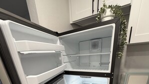 Eine moderne Küche mit weißen Schränken, einem integrierten Kühlschrank und einer Arbeitsfläche mit einem Blumentopf.