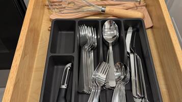 A drawer with a black tray containing various utensils, including forks, knives, and spoons.