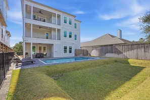 A two-story house with a backyard swimming pool, a fenced area, and a wooden fence.
