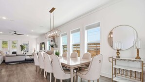 Un comedor moderno con una mesa blanca, sillas a juego y una araña.
