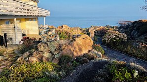 Una proprietà costiera con un edificio giallo, un vialetto in pietra e vista sul mare.