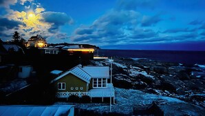 Una casa sulla costa con vista sull'oceano, un pontile in legno e un paesaggio innevato.
