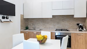 A modern kitchen with white cabinets, a built-in oven, and a dining table with chairs.
