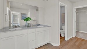 A modern bathroom with a large mirror, two sinks, and a shower area. - Naperville Luxury 3-bedroom (Naperville)
