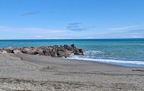 A beach with a rocky breakwater and calm sea. - Beach front apartment in Palomares (Cuevas de Almanzora)