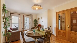 A dining area with a round table, chairs, a hanging light fixture, and a potted plant. - Sunny Beachside Escape by Minho s Guest (Povoa De Varzim)