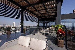 Terraza en la azotea con zona de estar, plantas en macetas y vistas del horizonte de la ciudad.