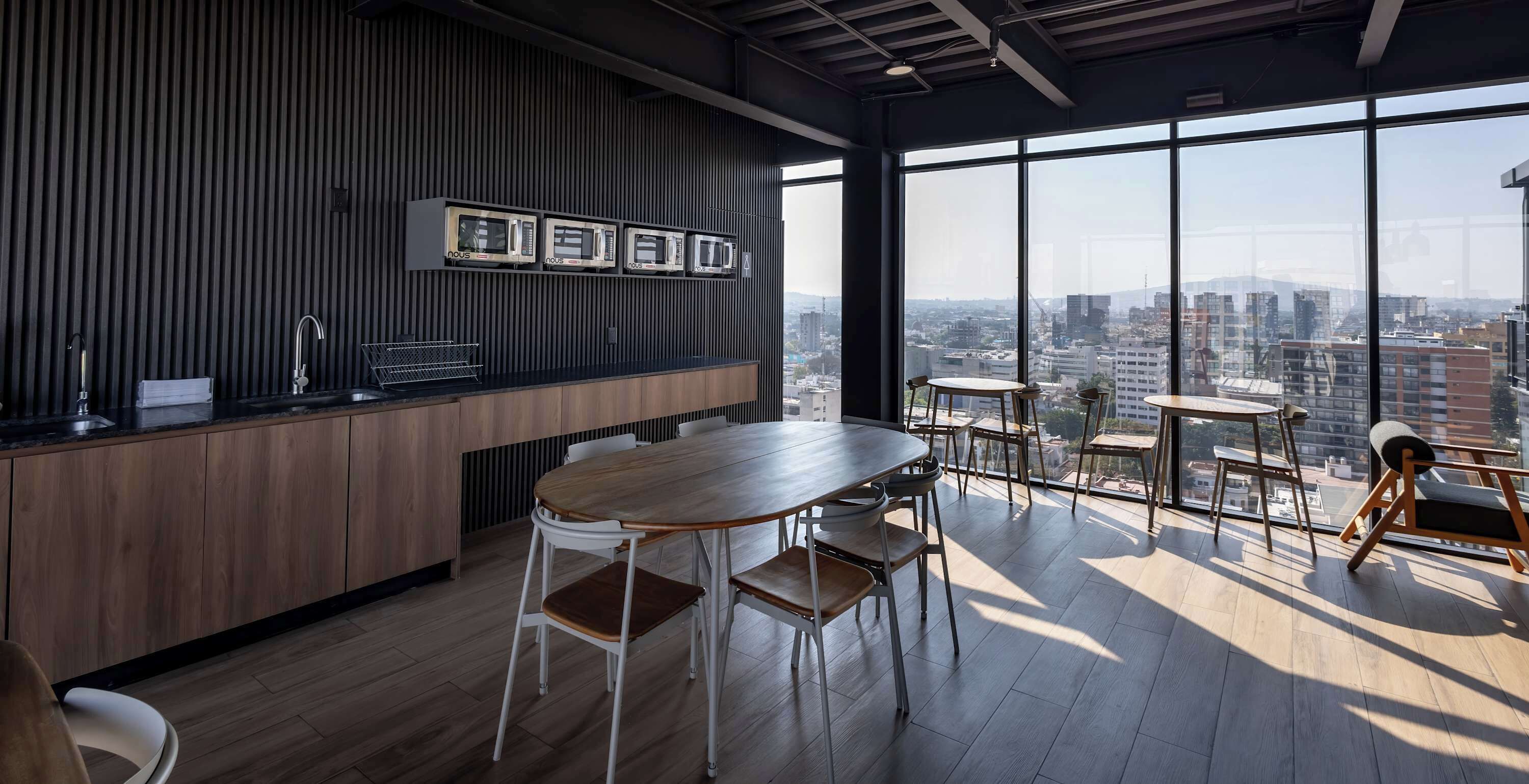 Una cocina moderna con encimera de madera, microondas integrado y un amplio ventanal con vistas a la ciudad.