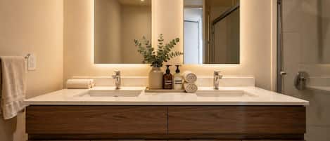 A bathroom with a double sink vanity, a mirror, and a plant.