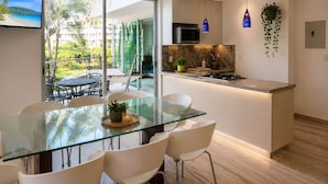 A modern kitchen with a glass dining table, white chairs, and a view of a tropical landscape through large windows. - Beach, Pool & Relaxation in Nuevo Vallarta (Nuevo Vallarta)