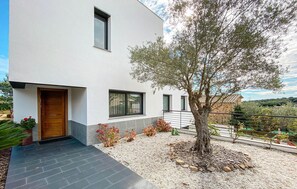 A modern two-story house with a wooden door, large windows, and a gravel garden with a tree. - Luxurious home in BLANES (BLANES)