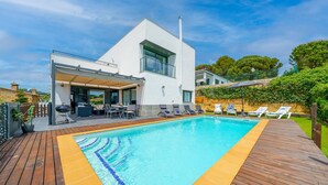 Een modern huis met een zwembad, buitenzitplaatsen en een overdekt terras.