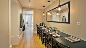 A dining area with a long table, chairs, hanging light fixtures, and a large mirror on the wall. - Bica 246 by luma (Lisboa)