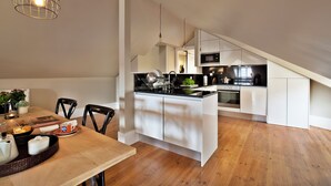 A modern kitchen with white cabinetry, a wooden dining table, and a hanging light fixture. - Bica 246 by luma (Lisboa)
