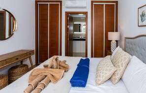 Ein Hotelzimmer mit Bett, Nachttisch, Lampe, Spiegel und einem durch eine offene Tür einsehbaren Badezimmer.