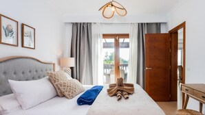 Ett hotellrum med en säng, ett sängbord, en lampa, en trädörr och utsikt över omgivningarna.