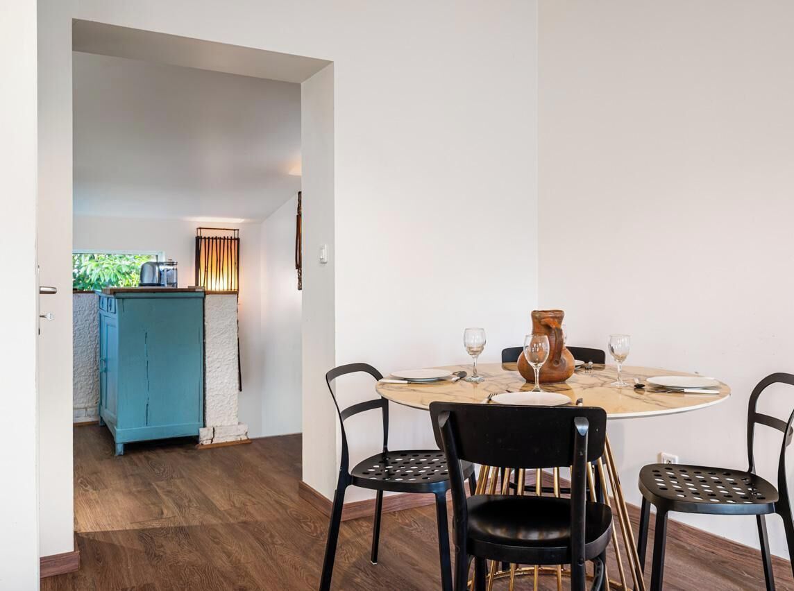 Un coin repas avec une table ronde, des chaises noires et un buffet bleu en arrière-plan.